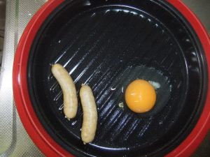 プレートにウインナーと卵の割ったものがのっている写真