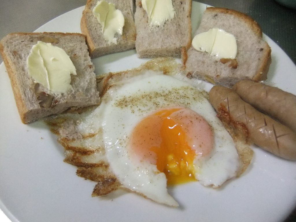 お皿に目玉焼き、ウインナー、パンがのっています。