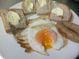 皿にパンと目玉焼きとウインナーがのっている写真