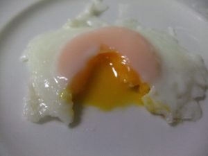 目玉焼きの黄身の部分を箸で割った写真