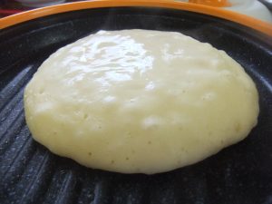 プレートの上に焼きかけのホットケーキの写真