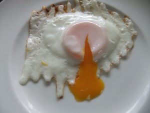 黄身が流れている目玉焼きの写真