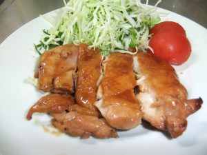 お皿に野菜と一緒に盛り付けられた鶏の照り焼きの写真