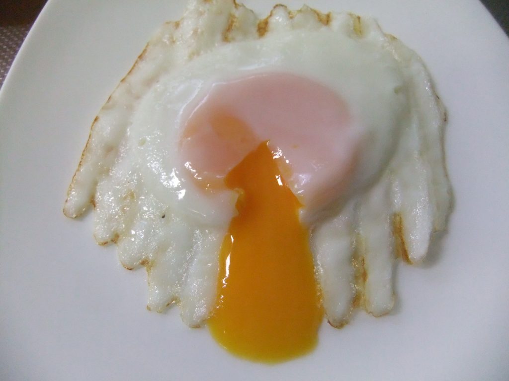 黄身が流れ出ている目玉焼きの写真