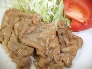 お皿にしょうが焼きとサラダの写真
